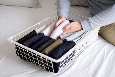 Closeup of hands of an man tidy up things in mesh storage containers. vertical storage of clothing.