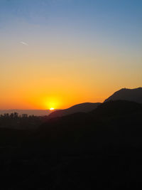 Scenic view of silhouette mountains against orange sky