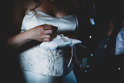 Midsection of woman holding decoration with ring in darkroom