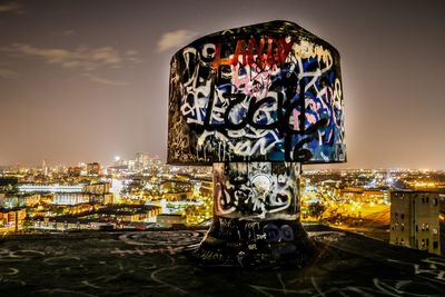 Illuminated cityscape by sea against sky at night