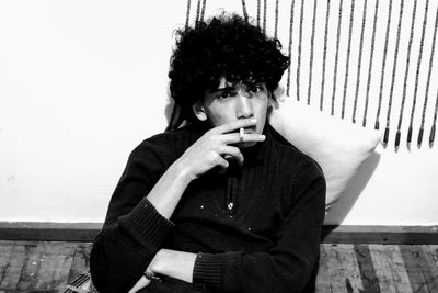 Portrait of boy smoking cigarette while sitting against wall