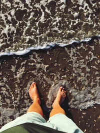 Low section of man standing on beach