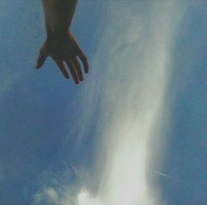 Low angle view of hands against blue sky