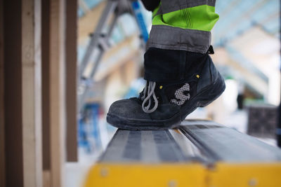 Low section of man wearing shoes standing on ladder