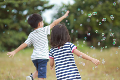 Rear view of children playing on field