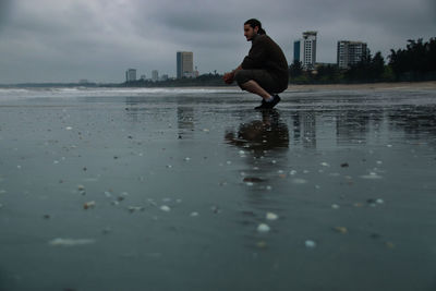 Full length of man standing on beach in city during rainy season