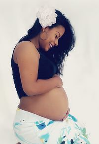 Side view of smiling young woman standing against white background