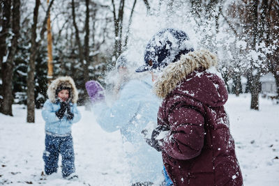 Happy family, friends, mother and kids having fun outdoors in winter snowy nature background. mom