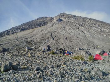 Group of people on rocky mountain against sky