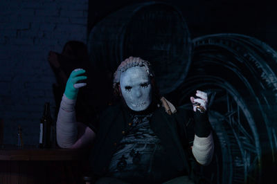 Man wearing halloween costumer sitting at table in darkroom