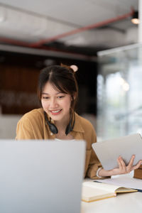 Young woman using laptop while sitting on table