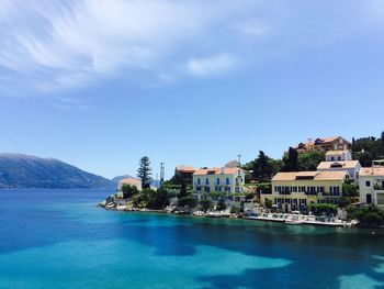 Residential buildings by blue lake against sky