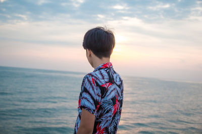 Rear view of man looking at sea against sky