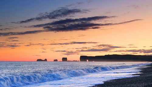 Scenic view of mountains by sea against sky during sunset