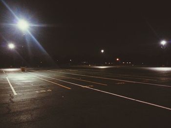 Illuminated road against sky at night