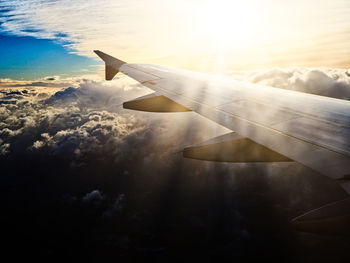 Close-up of airplane wing against sky during sunset