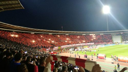 Crowd at illuminated stadium against sky at night