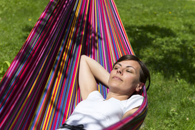 High angle view of mature woman lying on hammock during sunny day