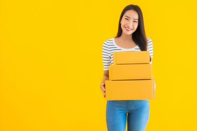 Portrait of a smiling young woman against yellow background