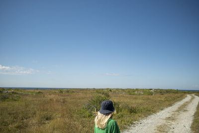 Blond girl on road leading to sea coast