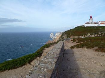 Lighthouse amidst sea and buildings against sky