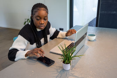 Portrait of young woman using mobile phone at home