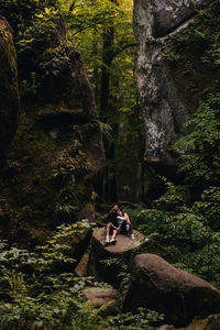 Rear view of man sitting on rock