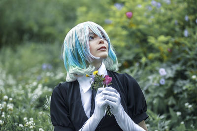 Beautiful woman standing by flowering plants