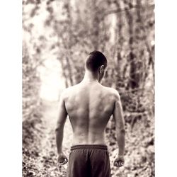 Rear view of shirtless man standing outdoors