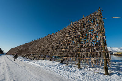 Built structure on snow covered field against clear blue sky
