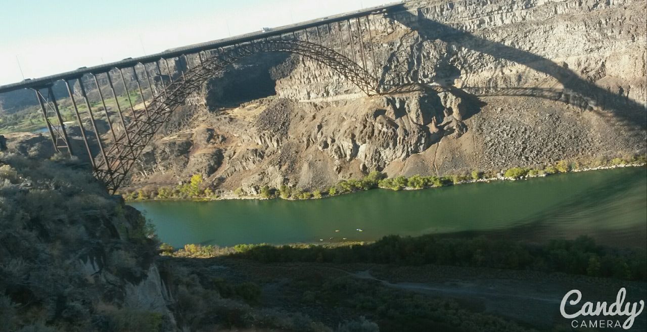 water, mountain, sky, tranquility, tranquil scene, nature, text, scenics, built structure, day, architecture, outdoors, beauty in nature, landscape, western script, rock - object, no people, building exterior, river, lake