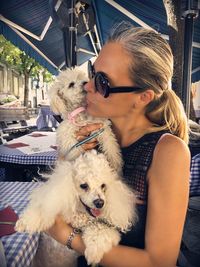 Smiling woman wearing sunglasses carrying dogs in city