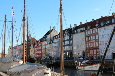 Sailboats moored on canal by buildings against sky in city