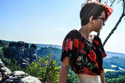 Young woman looking at mountain range against sky