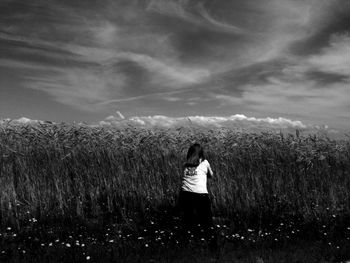 Man standing on field against cloudy sky