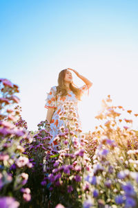 Beautiful pretty woman in a margaret aster flowers fields raise her hand to cover the sunlight
