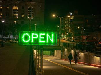 Information sign on illuminated road in city at night