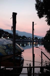 Silhouette boats moored in lake against sky at sunset