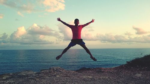 Full length of man jumping on shore against sky