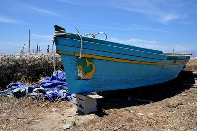 Ship moored on shore against blue sky