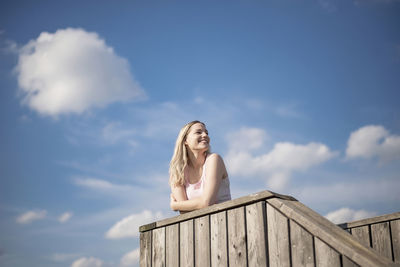 Portrait of woman against railing against sky