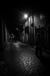 Rear view of man walking on walkway at night