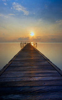 Pier over sea against sky during sunset