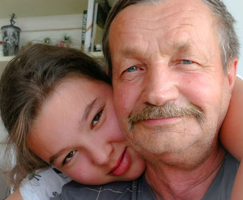 Close-up portrait of granddaughter with grandfather at home