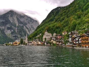 Buildings at waterfront against cloudy sky