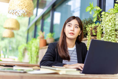 Portrait of young woman using phone while sitting on table