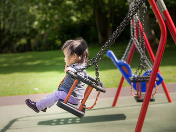 Side view of girl on swing in park