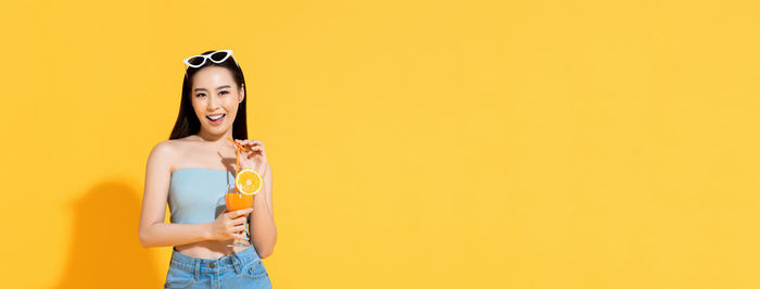 Portrait of a smiling young woman against yellow background