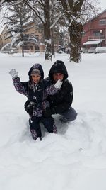 Happy father and son playing on snow covered field during winter