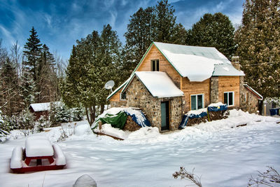Houses on snow covered field by buildings